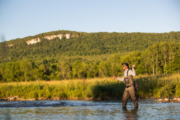 Man fly fishing in the summer in a river