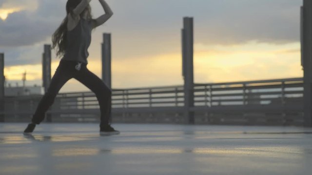 Urban dancer moves hip hop styles on a roof top. slowmotion handheld shot