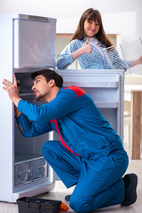 Man repairing fridge with customer