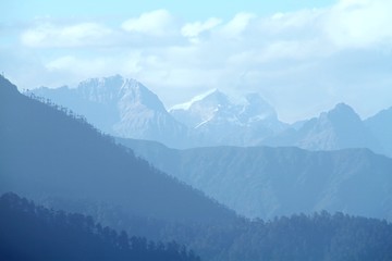 Morning mountain landscape with layer of mountain peaks covered with coniferous deciduous forests....