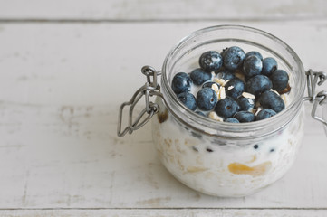 Overnight oats with fresh blueberry on wooden table, copy space. Easy oatmeal recipe for breakfast