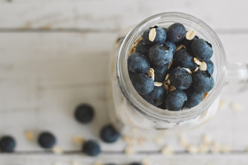 Oats with blueberry in a jar on wooden table. Overnight oats. Homemade yogurt with fresh berries. Healthy dessert