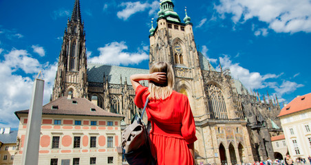 Fototapeta premium Beautiful girl in red dress travel in Prague, Church on background