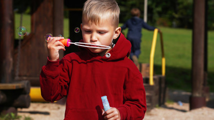 Portrait of cute little boy making soap bubbles.