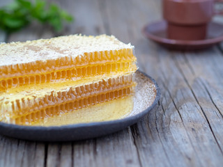 honey in honeycomb on plate on an old wooden table, close-up, side view
