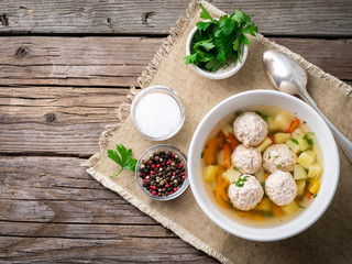 soup with meatballs in white plate on old wooden rustic grey table, top view, copy space