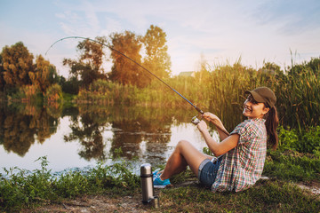 Happy woman is fishing with rod on lake