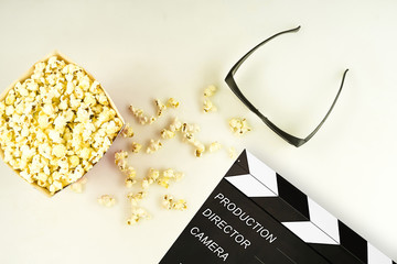 Cinema 3D glasses, popcorn and clapperboard on a white background