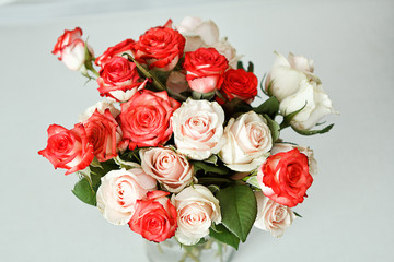 a bouquet of white and red roses in a glass vase stands on a white table