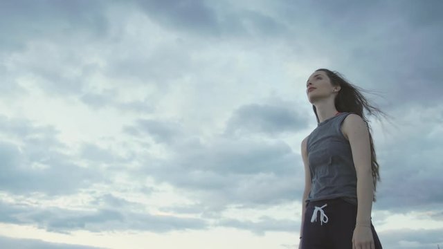 Young Girl dances in front a sunset blue sky with clouds