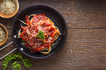 Spaghetti with tomato sauce on rustic wooden table , top view, copy space.