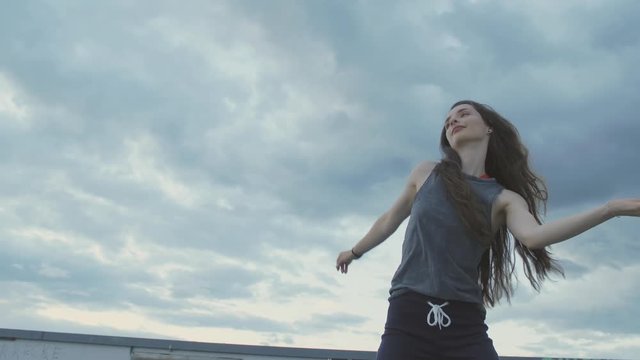 urban female dancer waving her hips and dancing in sunset blue sky
