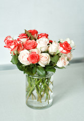 a bouquet of multi-colored roses stands in a glass vase on a white table in the kitchen