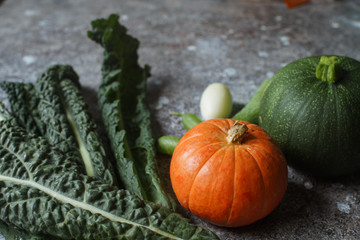 Fresh organic pumpkin, cucumbers and cabbage cale on dark stone table. Autumn harvest, healthy...