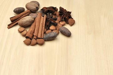 Top side view of ingredients for chocolate, cocoa beans, cinnamon, anise, apricot beans on natural wood background, copy space