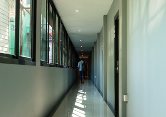 Leading lines view. The narrow walkway of the hotel. A man walking in the shadows at the destination.