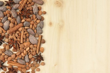 oncept with ingredients for chocolate, cocoa beans, cinnamon, anise, apricot beans on natural wood background, on the left with copy space, horizontal
