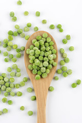 Guisantes congelados y una cuchara de madera sobre fondo blanco