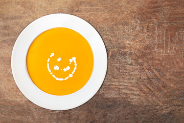 Squash soup with on wood table. Autumn Pumpkin soup served in a bowl, top view. Copy space.