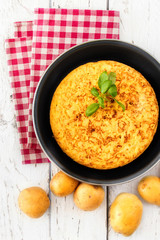 Spanish potato omelette called tortilla de patatas on a rustic wooden table, copyspace. Top view .