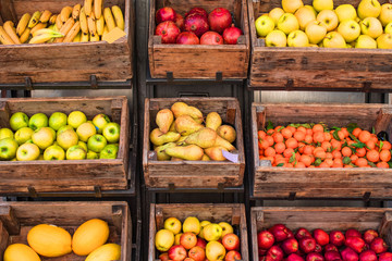 Assortment of fresh fruits and vegetables on market counter in a  wooden boxes