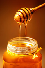 Fototapeta na wymiar Honey in jar with honey dipper on rustic wooden table background. Copy space.