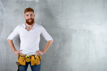 bearded brutal architect, engineer builder smiling at the background of a concrete wall