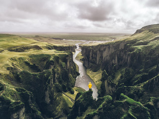 Man climbing on a rock in iceland to enjoy the panoramic view. Icelandic green hills and panoramas