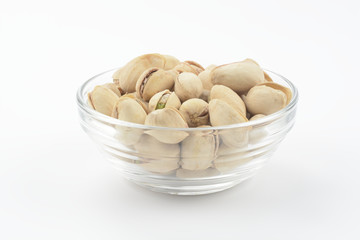 Pistachos en un bol de cristal sobre fondo blanco