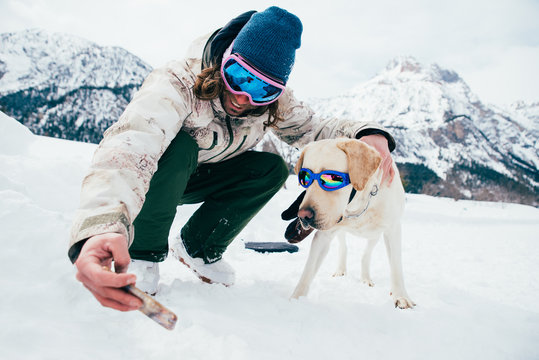 Friends playing with dog on the mountains, on th snowy ground