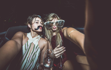 Party girls celebrate in Hollywood drinking champagne on a covertible car