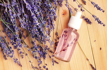 Homemade herbal body care lotion in bottle, viewed above with aromatic lavender blossom. Bunch of...