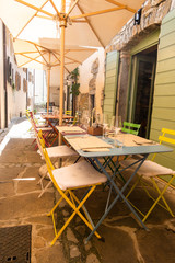 Fototapeta na wymiar Small caffee, restaurant in narrow street in a medieval town with colorful tables and chairs
