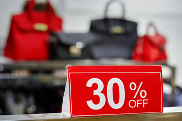 Shopping sale sign, 30 percent sale at a department store. Leather goods and handbags for girl and ladies on background. Seasonal sale off concept