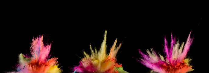 Explosions of coloured powder isolated on black background.