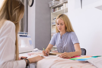 Obraz premium Fitting a wedding dress in the office of a seamstress. The bride and the designer of wedding dresses try on a dress
