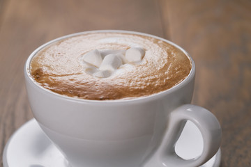 fresh cappuccino with marshmallow on wood oak table