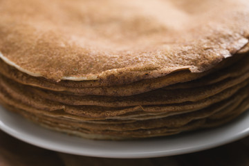 Closeup stack of fresh hot crepes or blinis on wood table