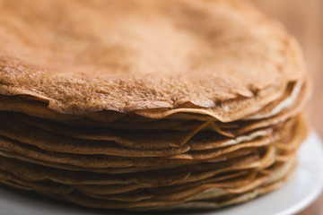 Closeup stack of fresh hot crepes or blinis on wood table