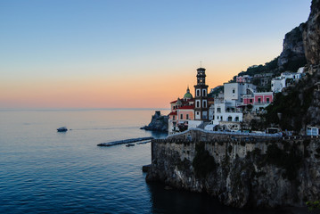 Atrani, a small town on Amalfi coast, shot during sunset, with vibrant white and pink houses and ancient bell tower standing high above them