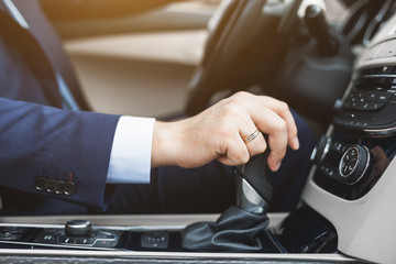 Businessman driving a car. hand close-up on gearbox, gearshift