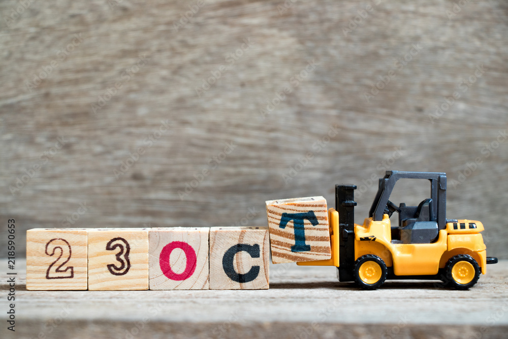 Wall mural Toy forklift hold block T to complete word 23 oct on wood background (Concept for calendar date in month October)