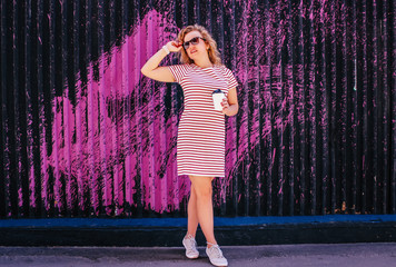 Young beautiful girl drinks coffee in the summer outdoors 