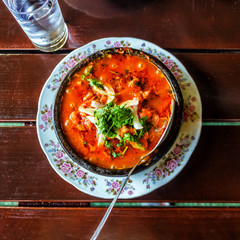 Shashushuli traditional homemade Georgian meat dish with vegetables with spicy sauce in a cast-iron pan frying pan on the background of a wooden table.