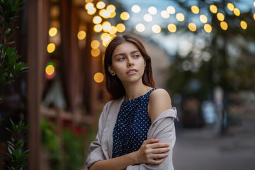 Fototapeta premium Romantic brunette girl posing at the city street on a lights background
