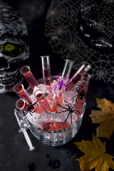 cocktail in glass tubes in an ice bucket with black spiders and a spider web in the background for Halloween party celebration
