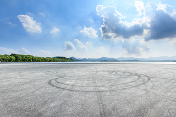 Empty asphalt square and mountain with lake on a sunny day