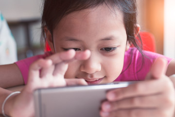 Smiling asian little girl playing  smartphone with happy