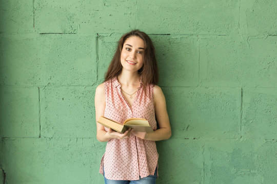 Literature, Education, People Concept - Female Student In Reading The Book Over The Green Wall