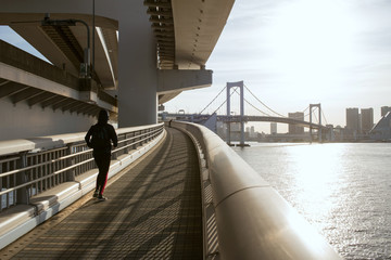 Woman running on Tokyo Rainbow Bridge at...